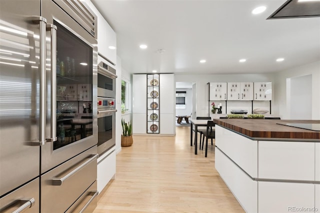 8612 W 69th Pl, Arvada, CO 80004 - kitchen featuring stainless steel appliances, wood counters, white cabinets, light wood-style flooring, and recessed lighting