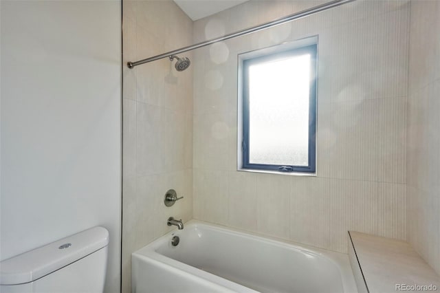 bathroom featuring toilet and tiled shower / bath