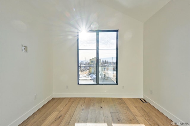 empty room with light hardwood / wood-style floors and vaulted ceiling