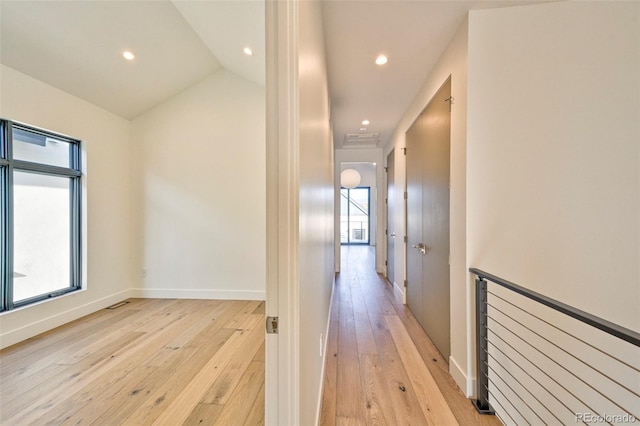 hallway with light wood-type flooring, plenty of natural light, and lofted ceiling