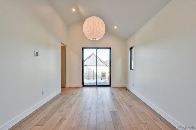 spare room featuring light wood-type flooring and high vaulted ceiling