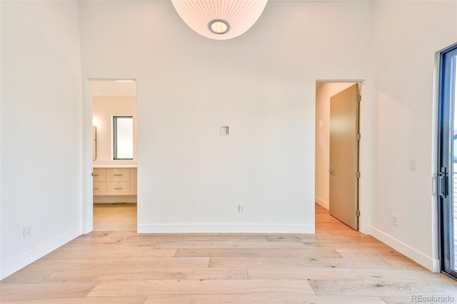 unfurnished bedroom featuring ensuite bathroom and light hardwood / wood-style flooring