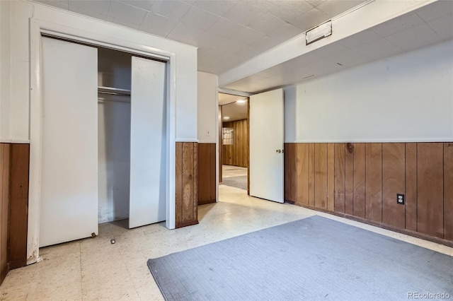 12576 W 7th Ave, Lakewood, CO 80401 - unfurnished bedroom featuring a wainscoted wall, wood walls, tile patterned floors, and a closet