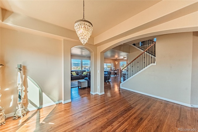 2459 Delicato Ct, Colorado Springs, CO 80921 - spare room featuring arched walkways, wood finished floors, stairs, and a chandelier