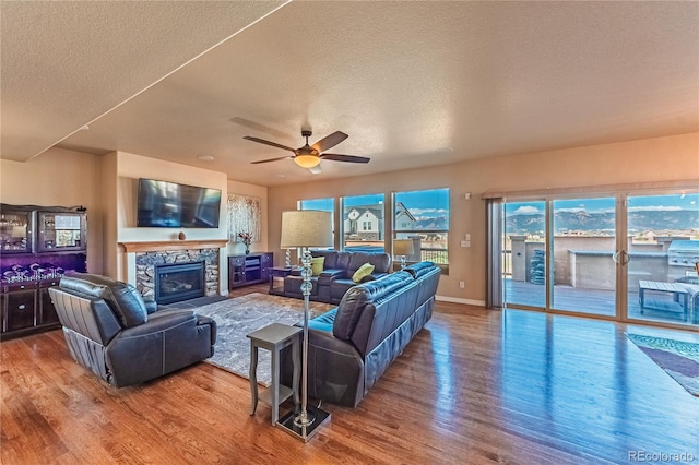 2459 Delicato Ct, Colorado Springs, CO 80921 - living area featuring a textured ceiling, wood finished floors, a ceiling fan, a fireplace, and baseboards