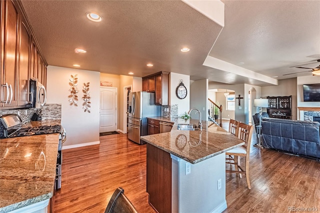 2459 Delicato Ct, Colorado Springs, CO 80921 - kitchen featuring a sink, appliances with stainless steel finishes, wood finished floors, a breakfast bar area, and a textured ceiling