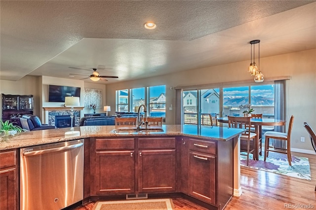2459 Delicato Ct, Colorado Springs, CO 80921 - kitchen with stainless steel dishwasher, a sink, light wood finished floors, ceiling fan, and a textured ceiling