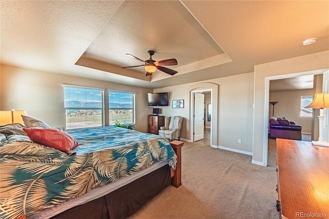 2459 Delicato Ct, Colorado Springs, CO 80921 - bedroom featuring a raised ceiling, light colored carpet, baseboards, arched walkways, and ceiling fan