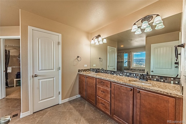 2459 Delicato Ct, Colorado Springs, CO 80921 - bathroom with double vanity, baseboards, tile patterned flooring, a walk in closet, and backsplash