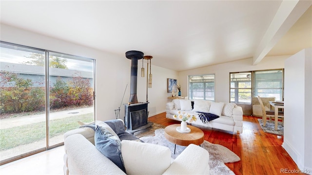 living room featuring hardwood / wood-style floors, vaulted ceiling with beams, and a wood stove