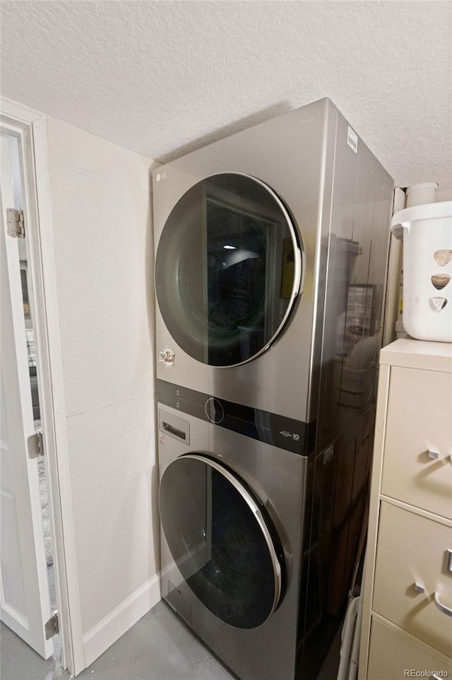 2865 Newland St, Wheat Ridge, CO 80214 - laundry area featuring stacked washer / drying machine, a textured ceiling, and baseboards