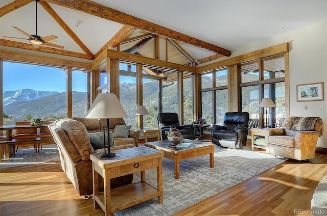 sunroom / solarium with vaulted ceiling with beams, ceiling fan, a mountain view, and a wealth of natural light