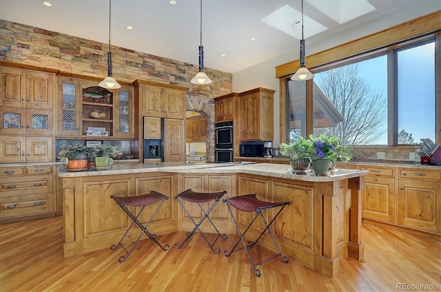 kitchen featuring paneled built in refrigerator, double wall oven, a breakfast bar, and decorative light fixtures