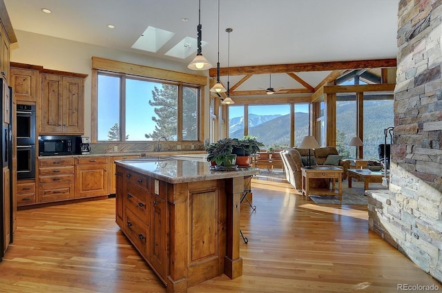 kitchen with pendant lighting, a breakfast bar area, light stone countertops, a kitchen island, and a mountain view