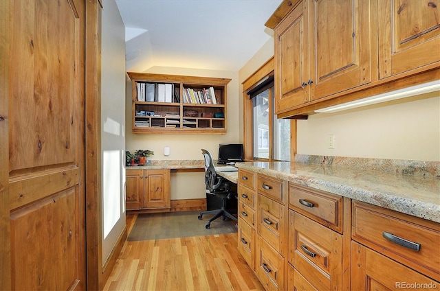 home office with built in desk and light hardwood / wood-style floors