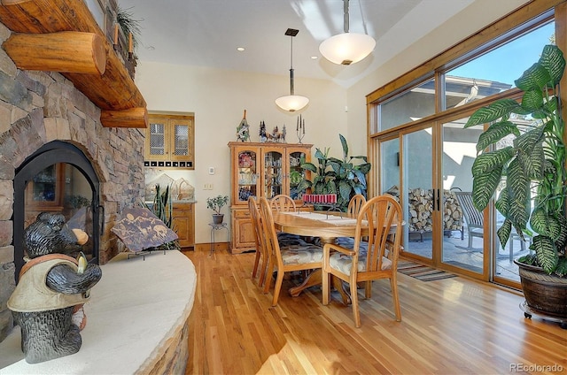 dining room with a stone fireplace, light hardwood / wood-style floors, and french doors