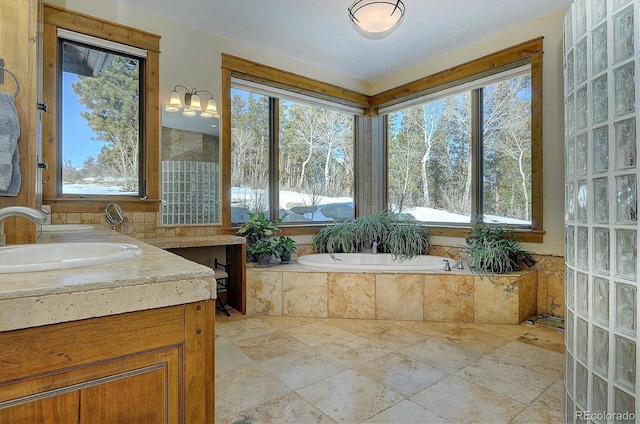 bathroom with vanity, a wealth of natural light, and tiled bath