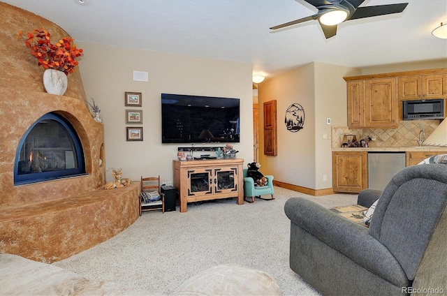 carpeted living room featuring sink, a premium fireplace, and ceiling fan