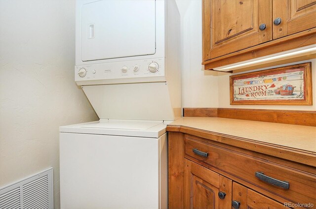 laundry room featuring cabinets and stacked washer and dryer