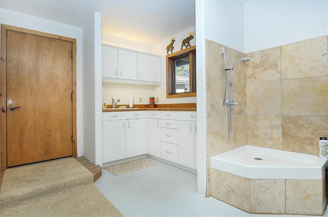 bathroom featuring vanity, concrete flooring, and a tile shower