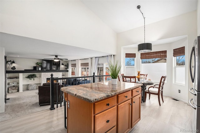 15776 E 107th Way, Commerce City, CO 80022 - kitchen featuring freestanding refrigerator, a center island, brown cabinets, high vaulted ceiling, and a ceiling fan