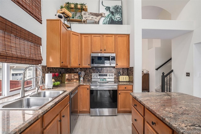 15776 E 107th Way, Commerce City, CO 80022 - kitchen featuring stainless steel appliances, a sink, decorative backsplash, dark stone countertops, and brown cabinets