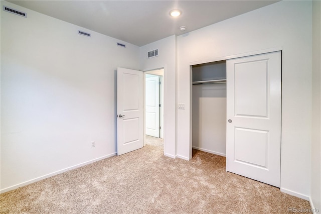 unfurnished bedroom with light carpet and a closet