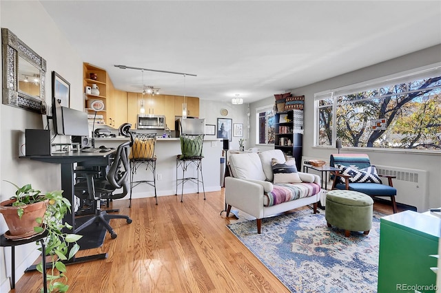 living room with a chandelier, radiator heating unit, and light hardwood / wood-style floors