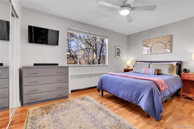 bedroom with ceiling fan, radiator heating unit, and light hardwood / wood-style flooring