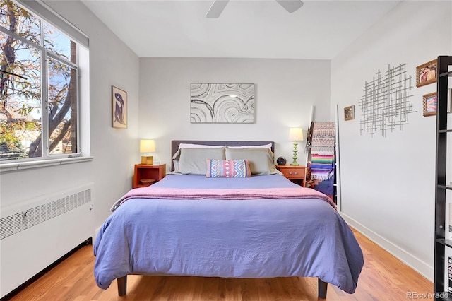 bedroom with light hardwood / wood-style flooring, radiator heating unit, and ceiling fan