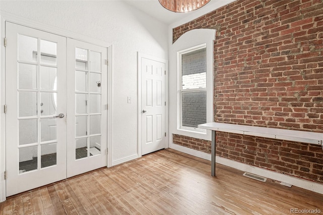 entrance foyer with light wood-style flooring, baseboards, and brick wall