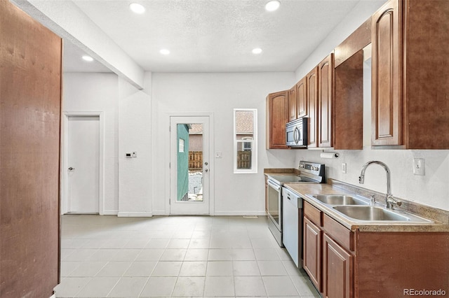 kitchen with a sink, stainless steel appliances, brown cabinets, recessed lighting, and light tile patterned floors