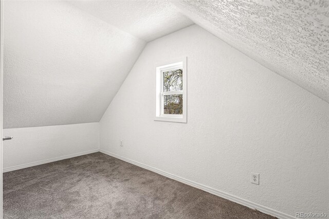 bonus room with a textured ceiling, vaulted ceiling, baseboards, and carpet