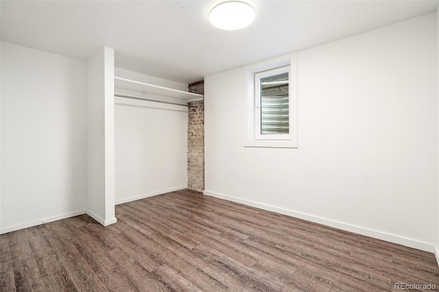 unfurnished bedroom featuring wood finished floors, a closet, and baseboards
