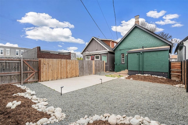 back of house with a fenced backyard, a chimney, a patio area, and a gate