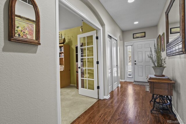 foyer entrance with a textured wall, wood finished floors, baseboards, and french doors