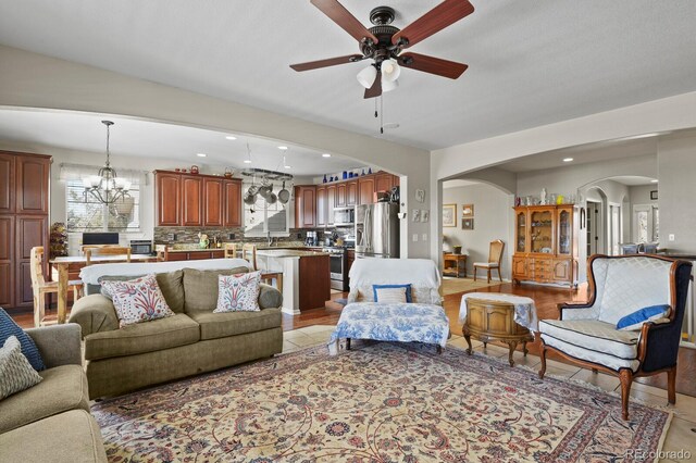 living room with recessed lighting, arched walkways, and ceiling fan with notable chandelier