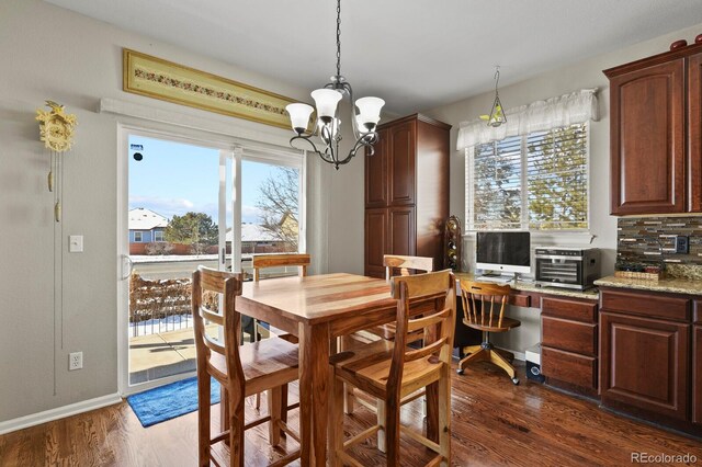 dining space with a toaster, dark wood-type flooring, a notable chandelier, and baseboards