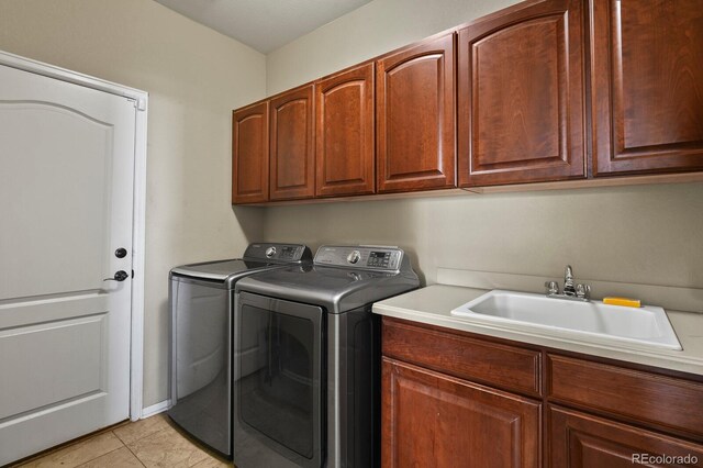 washroom featuring cabinet space, light tile patterned floors, separate washer and dryer, and a sink