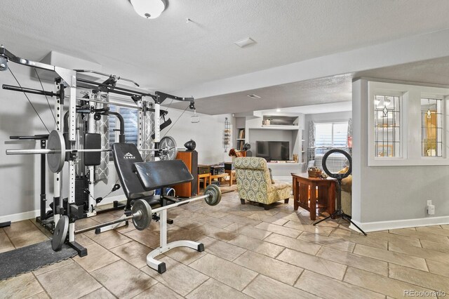 exercise room with baseboards and a textured ceiling