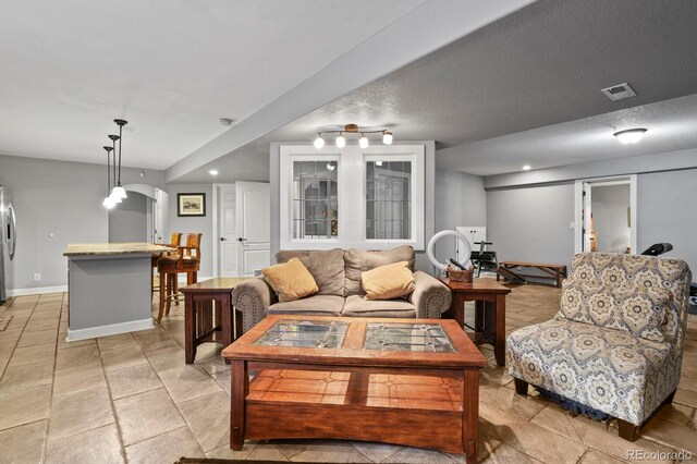 living room with visible vents, baseboards, recessed lighting, arched walkways, and a textured ceiling