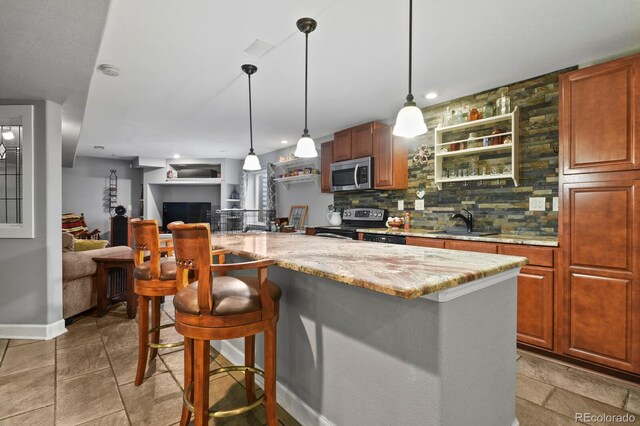 kitchen with a breakfast bar area, light stone countertops, a sink, stainless steel appliances, and backsplash