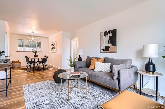 living room with arched walkways, baseboards, and wood finished floors