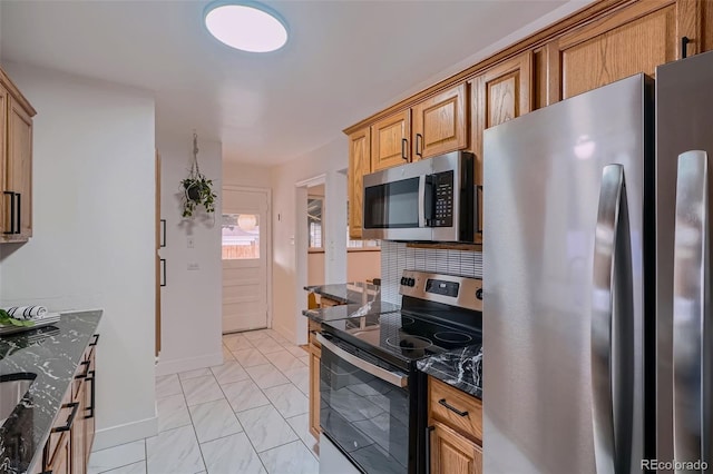 kitchen with dark stone counters, appliances with stainless steel finishes, backsplash, and baseboards