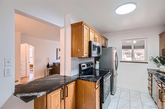 kitchen featuring arched walkways, brown cabinets, stainless steel appliances, backsplash, and dark stone counters