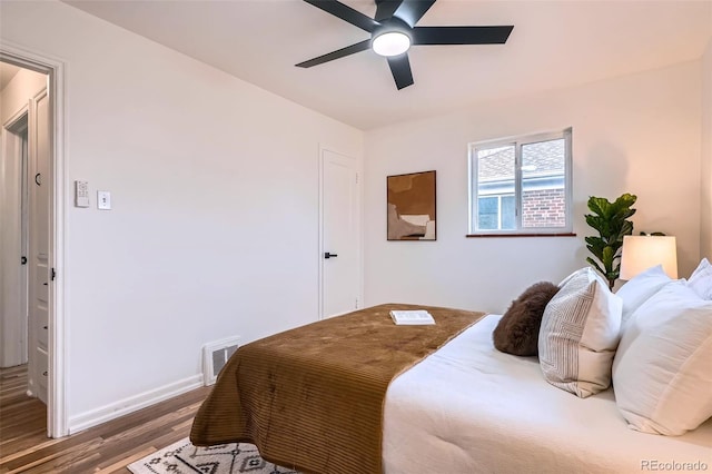 bedroom featuring visible vents, ceiling fan, baseboards, and wood finished floors