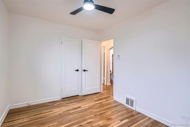 unfurnished bedroom featuring a ceiling fan, visible vents, light wood-style flooring, and baseboards