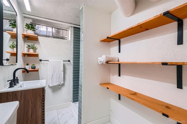 full bathroom featuring a textured ceiling, marble finish floor, vanity, and baseboards