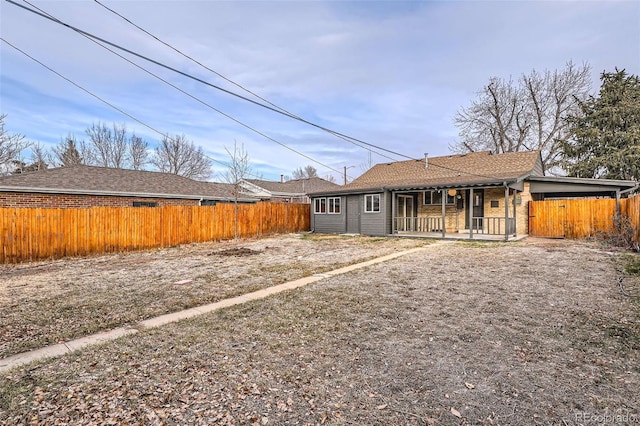 rear view of house featuring a porch and fence