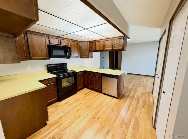 53 Douglas Dr S, Broomfield, CO 80020 - kitchen featuring black appliances, a peninsula, light wood-style flooring, light countertops, and a sink